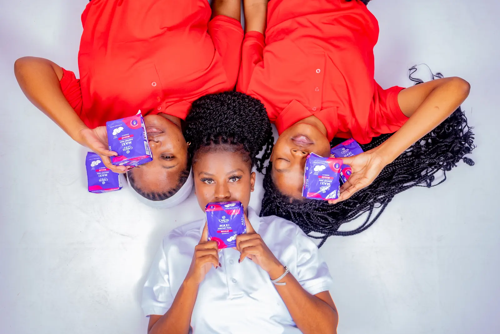 Young women in TruCam red and white holding sanitary towel packs