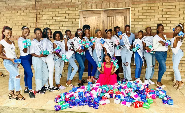 Pageant contestants with a large pile of donated sanitary towels